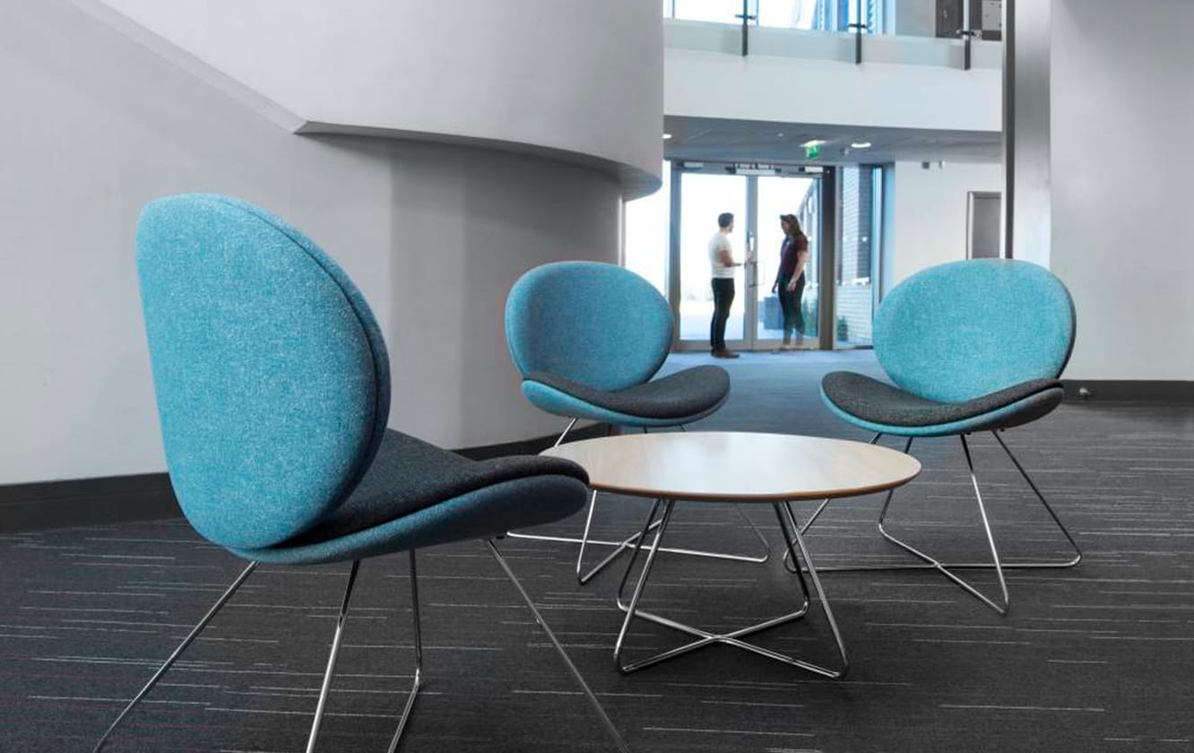 Three blue lounge chairs for offices in an office with a table in the middle.