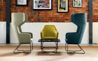 Three colourful chairs in a room with a brick wall.