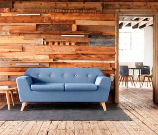A blue sofa in front of a wooden wall.