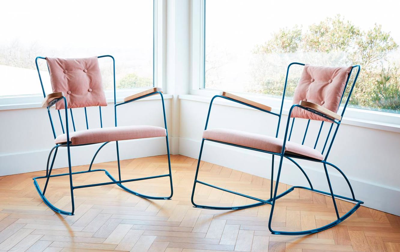 Two pink rocking chairs in front of a window.