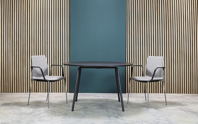 Two chairs and a table in front of a wall.
