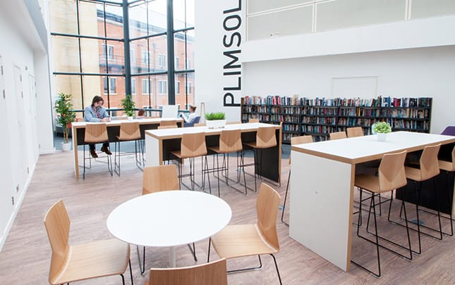 A library with tables and chairs in the middle of the room.