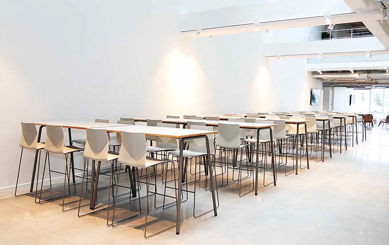 A long line of tables and counter chairs in a room.