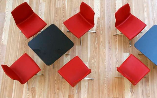 A group of red chairs on a wooden floor.