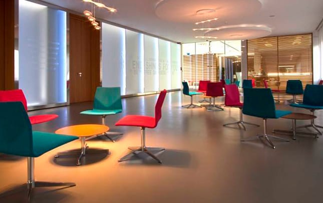 A reception room with colourful chairs and a glass wall.