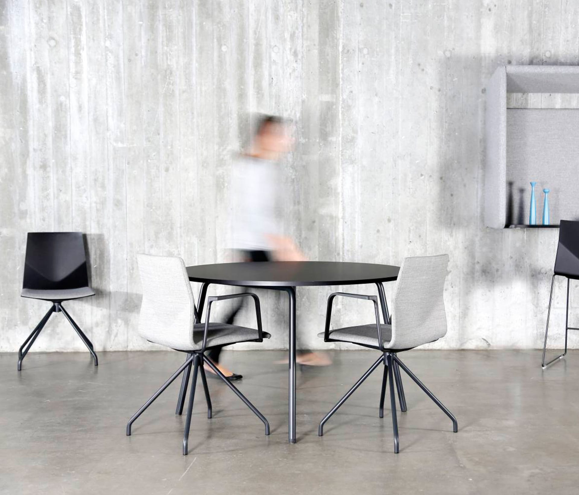 A table and chairs in a room with a concrete wall.
