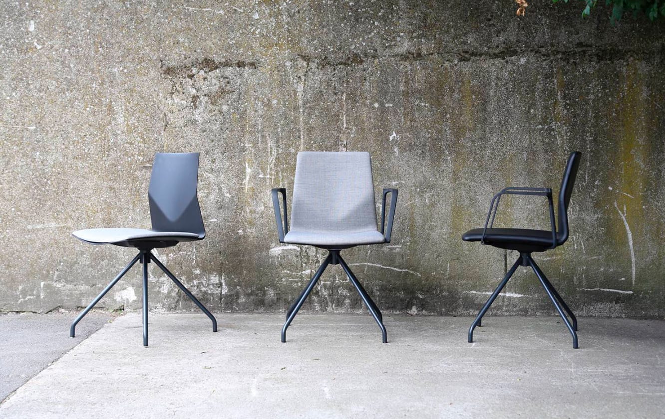 Three black and white chairs in front of a concrete wall.