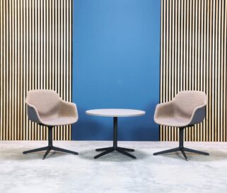 Two office desk chairs and a table in front of a blue wall.