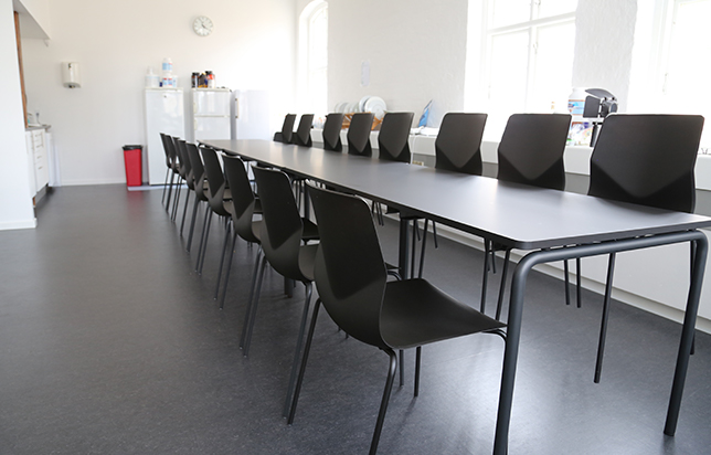 A long row of black meeting table chairs in a classroom.