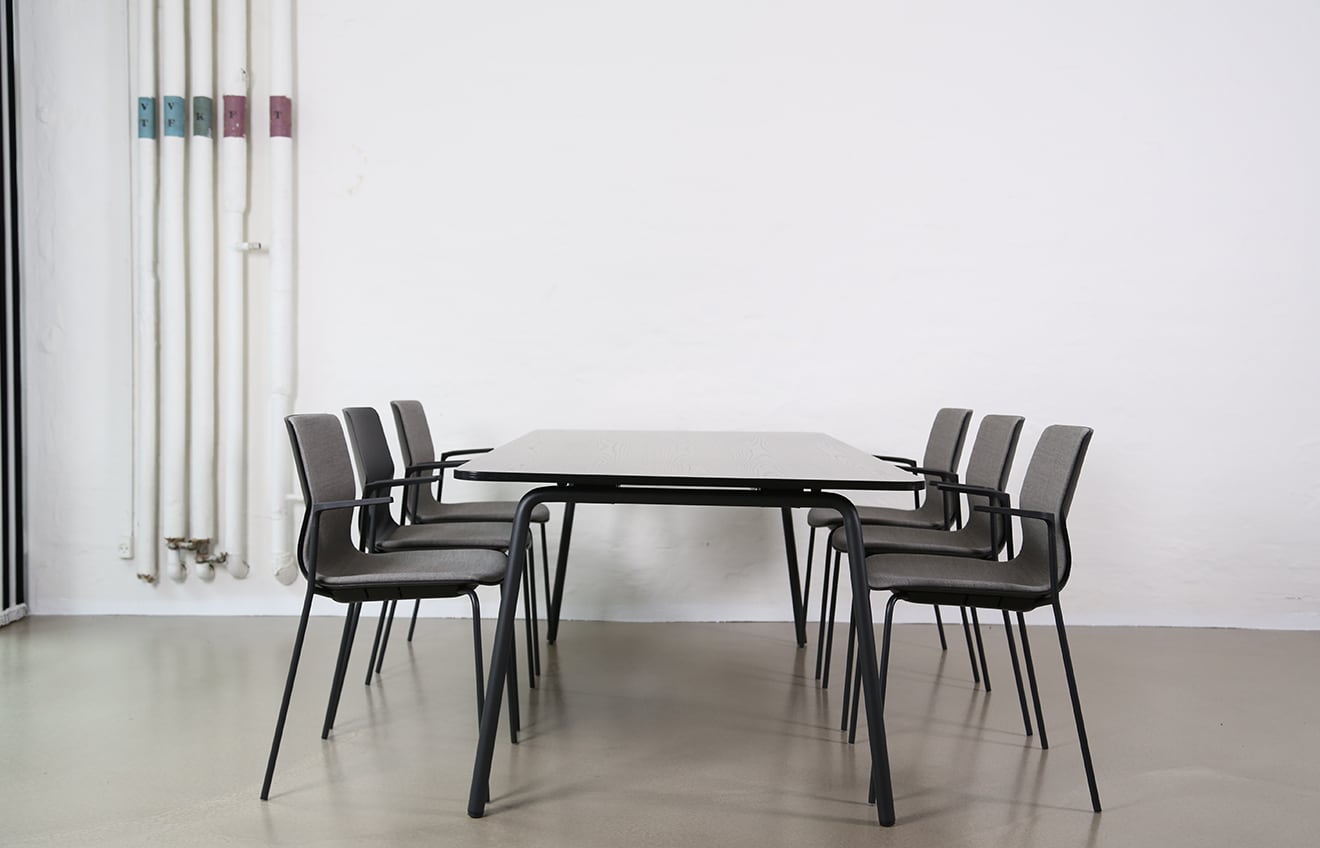 A table and meeting table chairs in a room with a radiator.