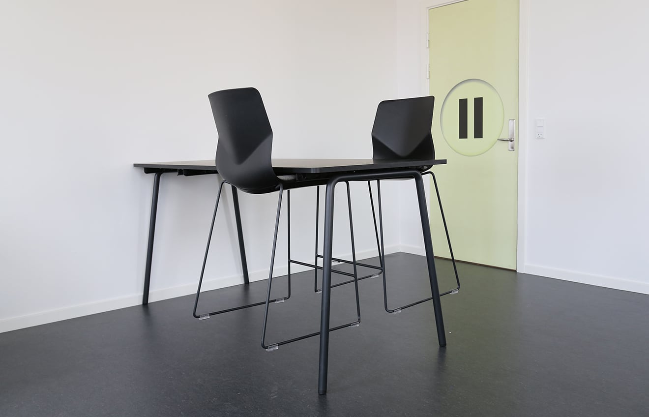 Two black counter chairs and a table in an empty room.