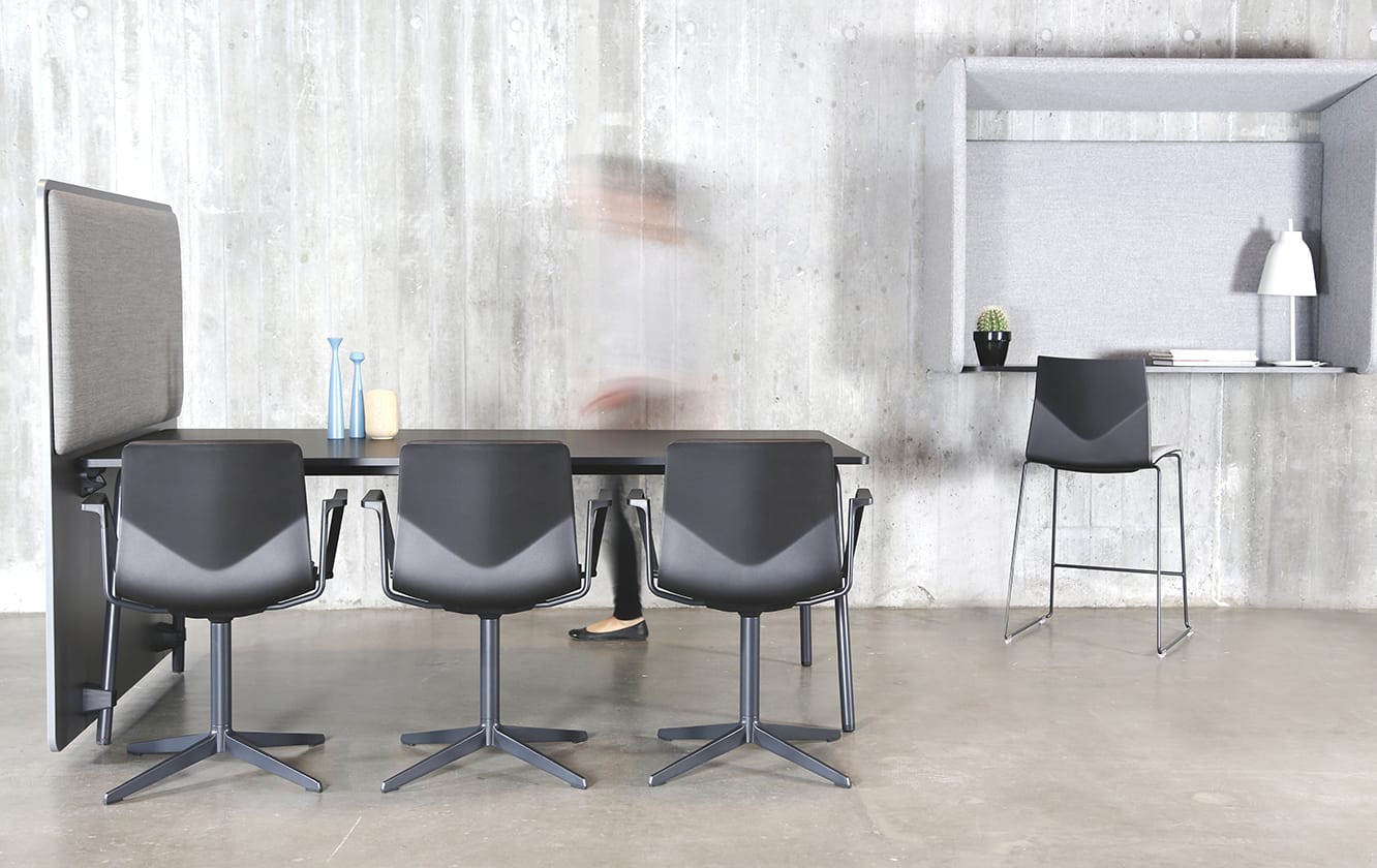 A black table and chairs in a room with a concrete wall.