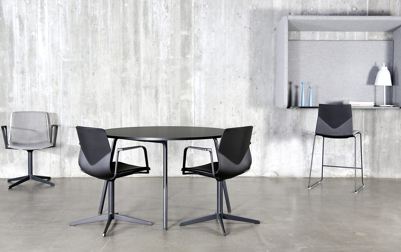 Three chairs and a table in a concrete room.