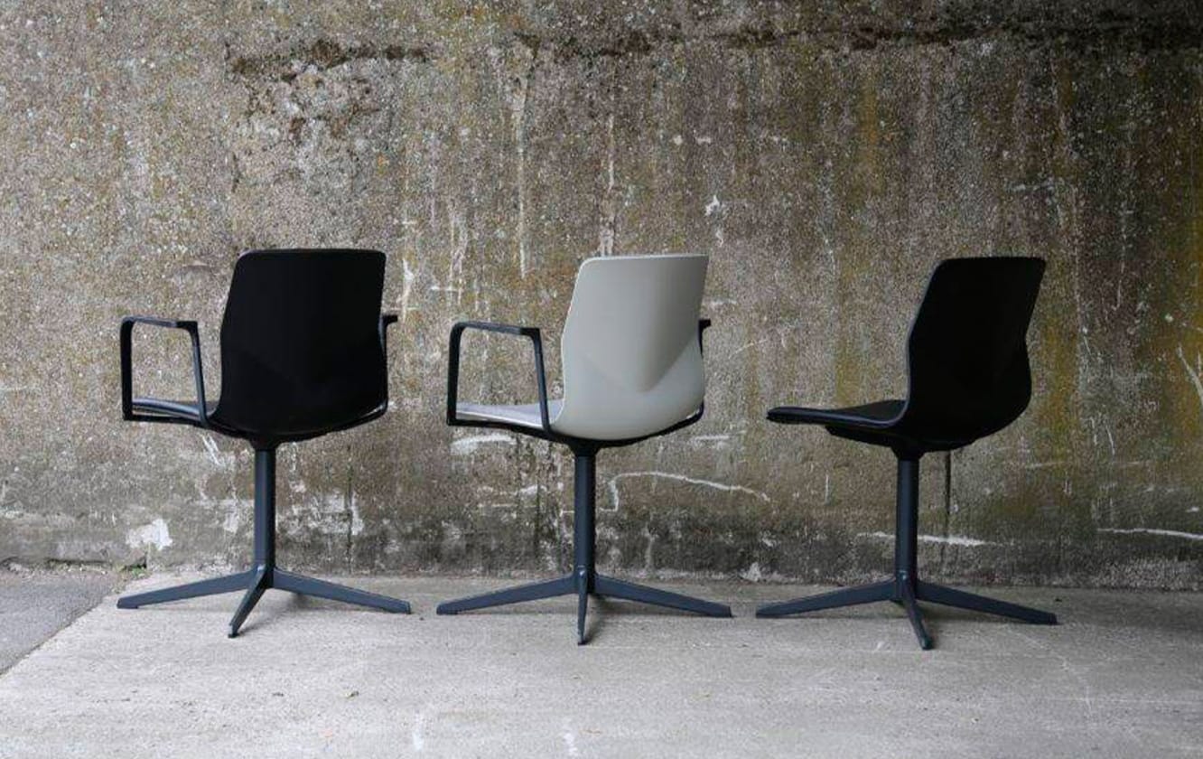 Three black and white chairs in front of a concrete wall.