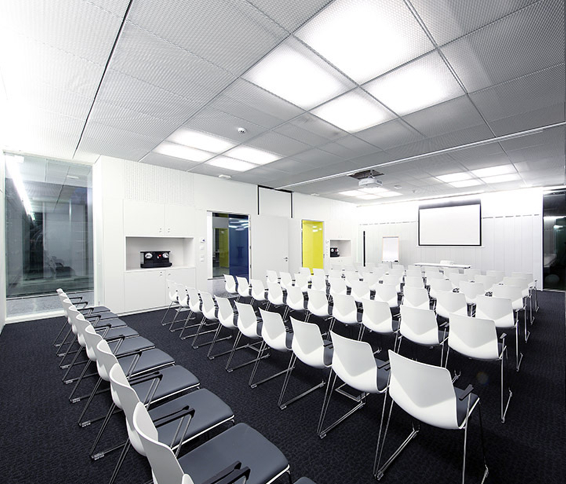 A conference room with white chairs and a projection screen.