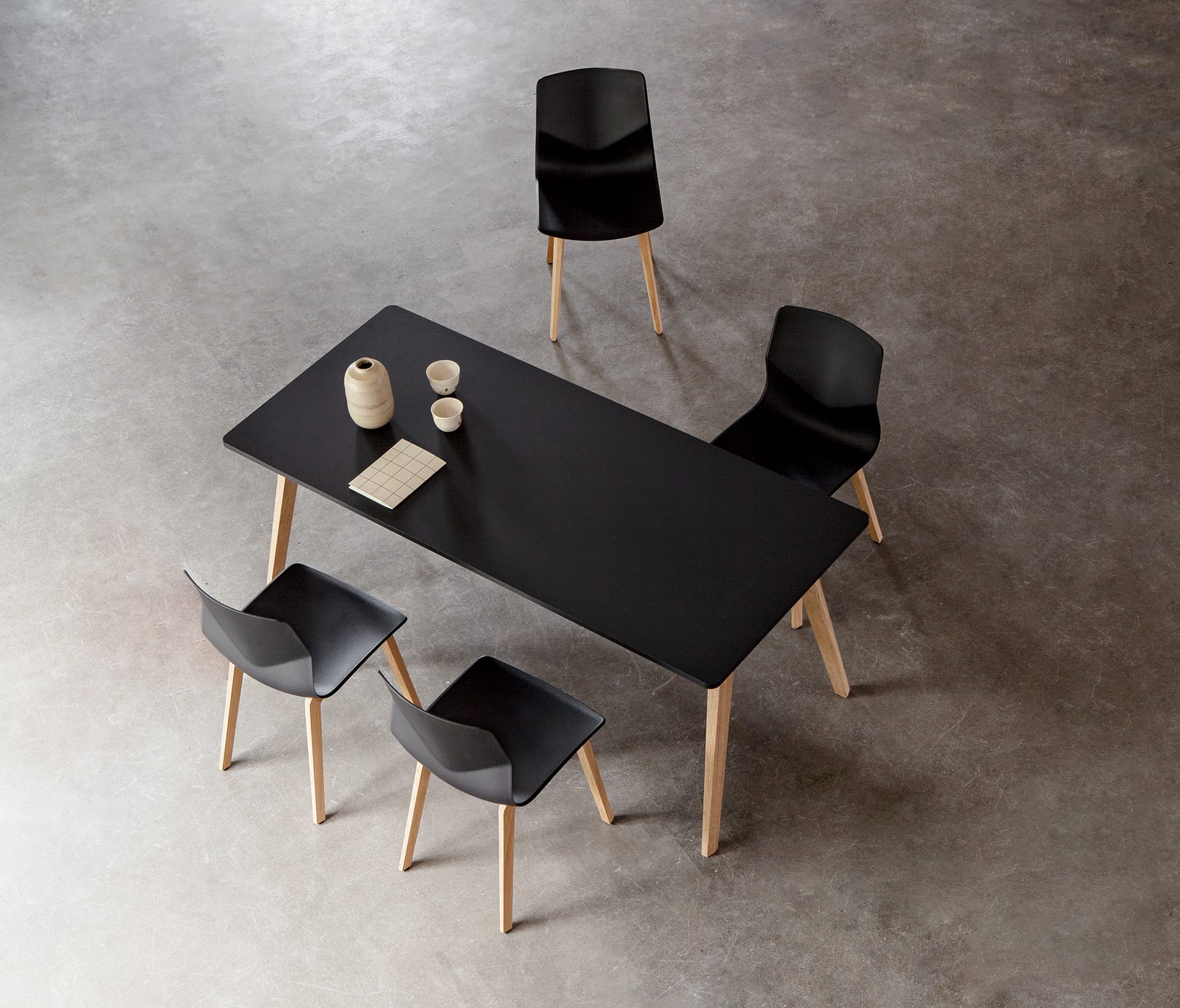 A black table with four black office desk chairs.