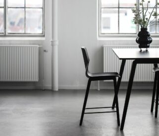 A dining table with two black stools in front of a window.