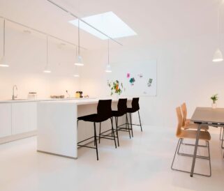 A white kitchen with a table and counter chairs.