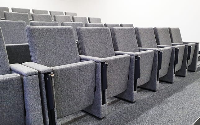 A purple carpeted auditorium with rows of tip up seating