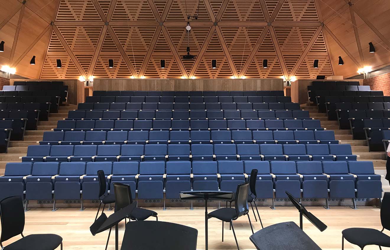 A large auditorium with rows of auditorium seating and chairs.