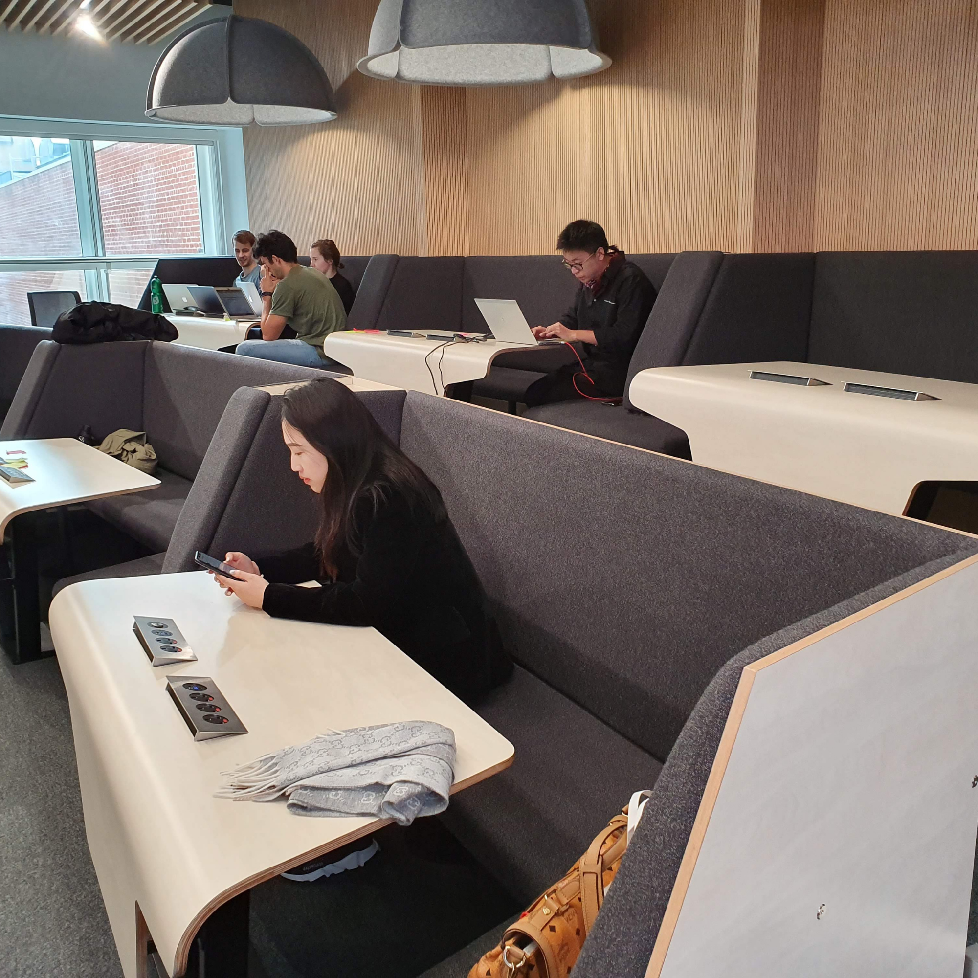 A group of people using laptops in a conference room full of work booths