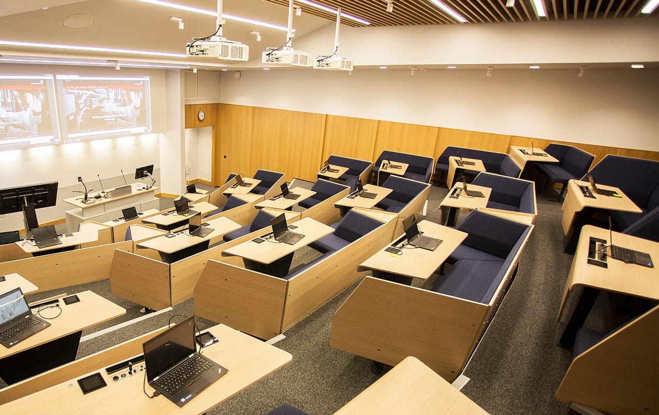 A lecture hall with blue lecture hall seating and desks