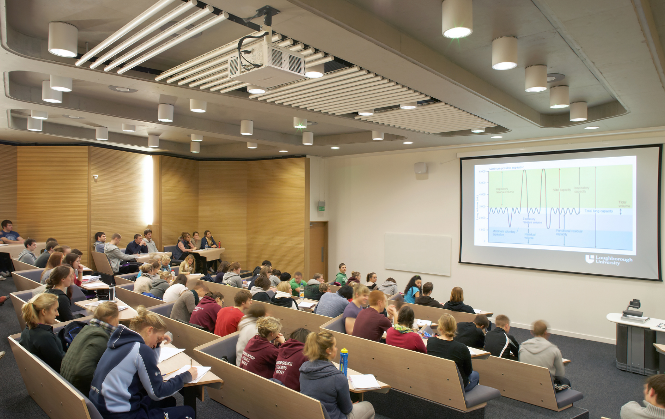 A large lecture hall with lecture hall seating filled with students