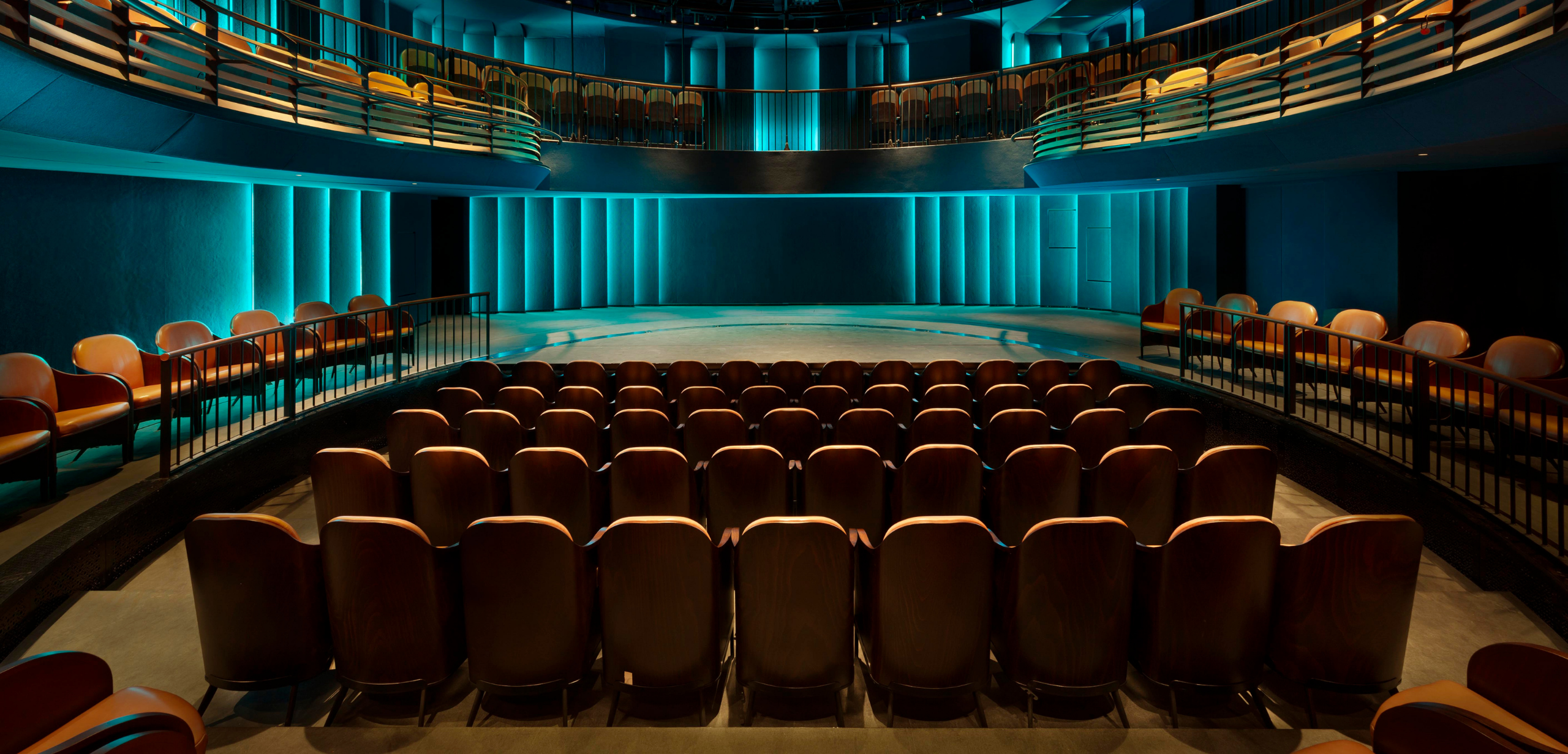 An auditorium with rows of auditorium seating and blue lighting.