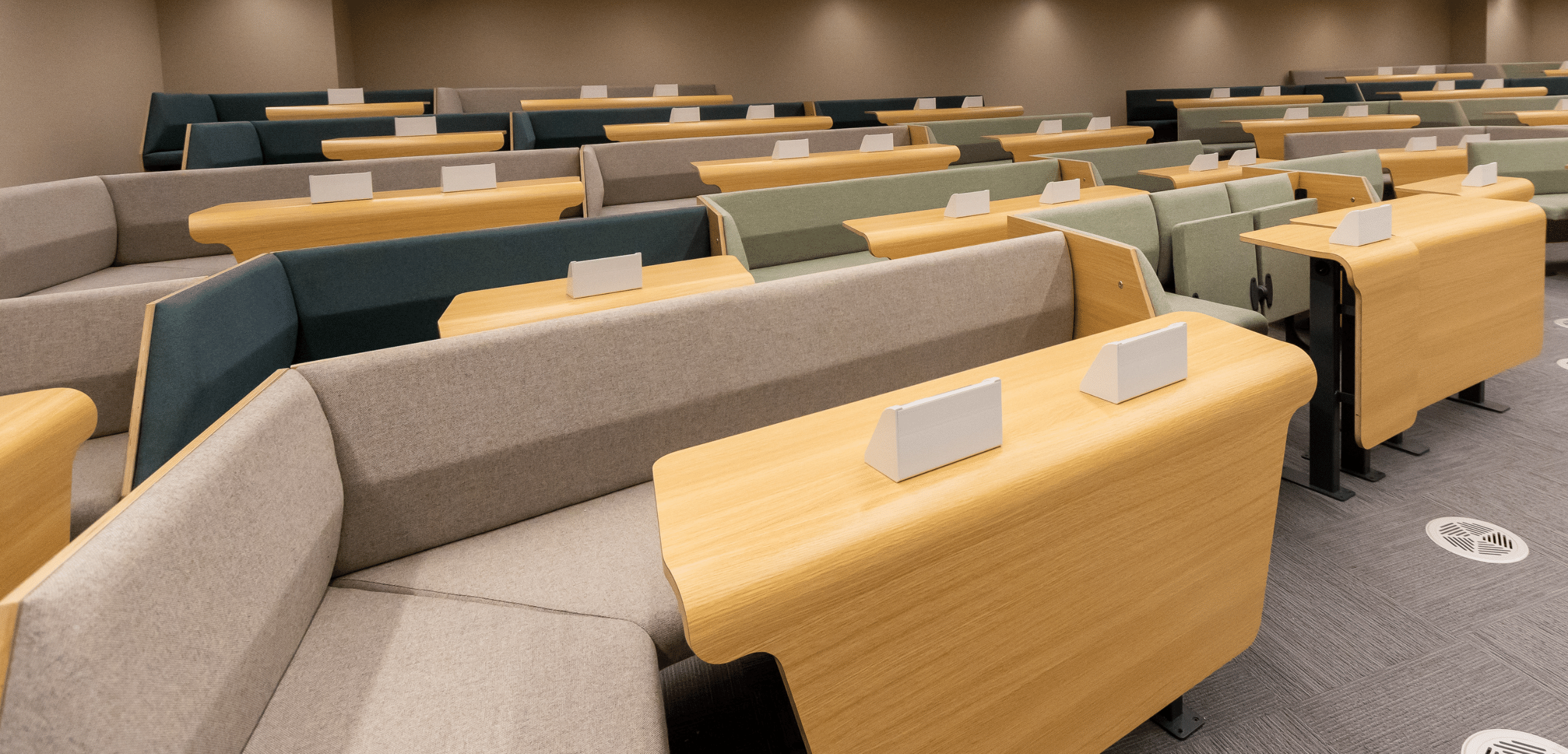 A lecture hall with grey lecture hall seating and green walls.