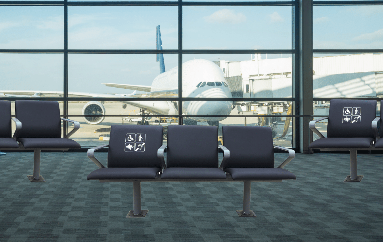 Airport terminal seating consisting of four black chairs in front of a window with an airplane in the background.