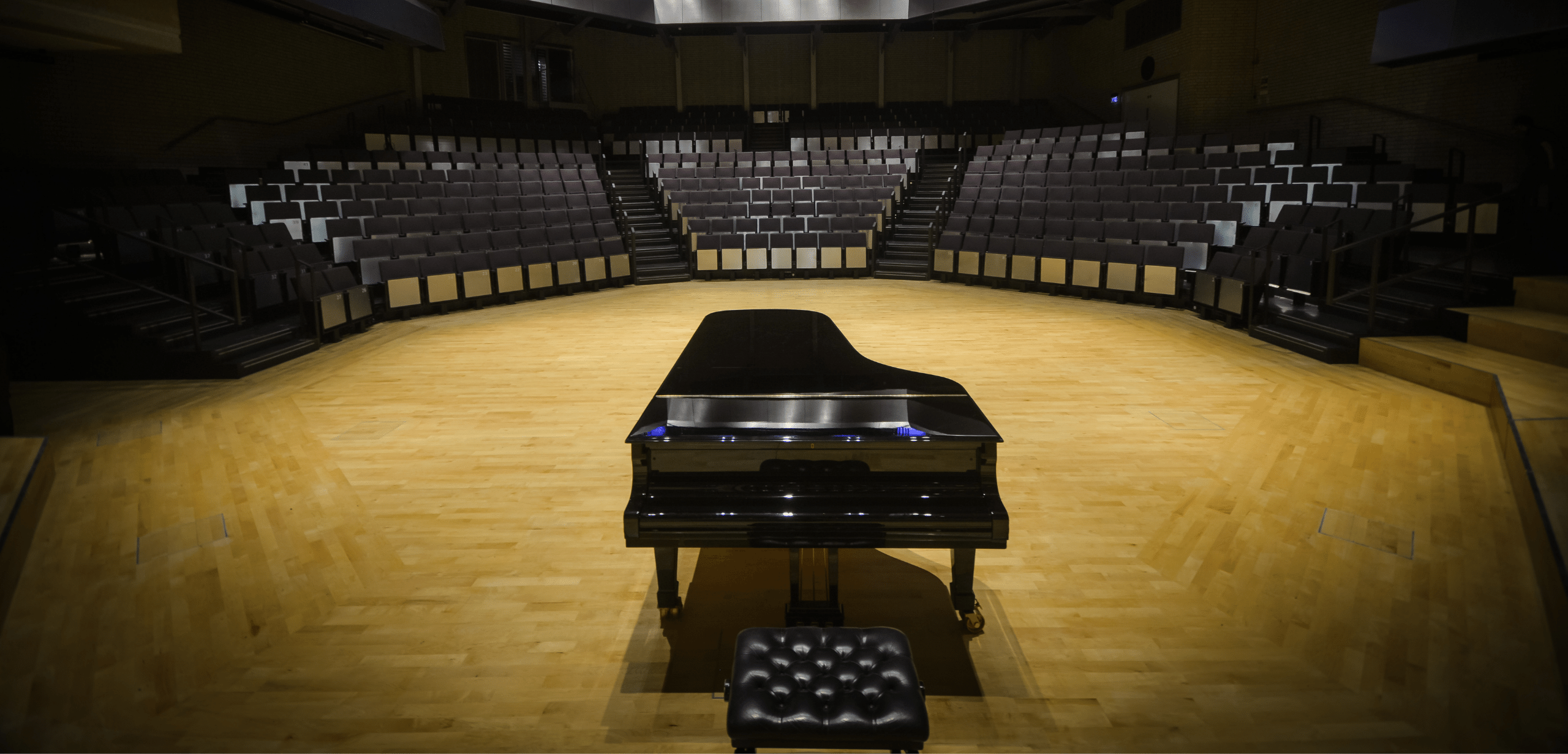 An empty auditorium with a piano in the middle.