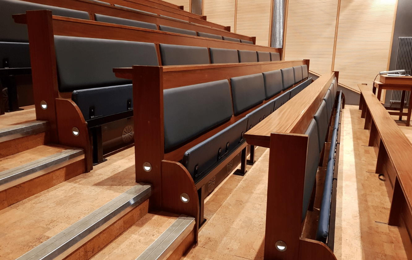 A row of blue leather auditorium seating in a room.