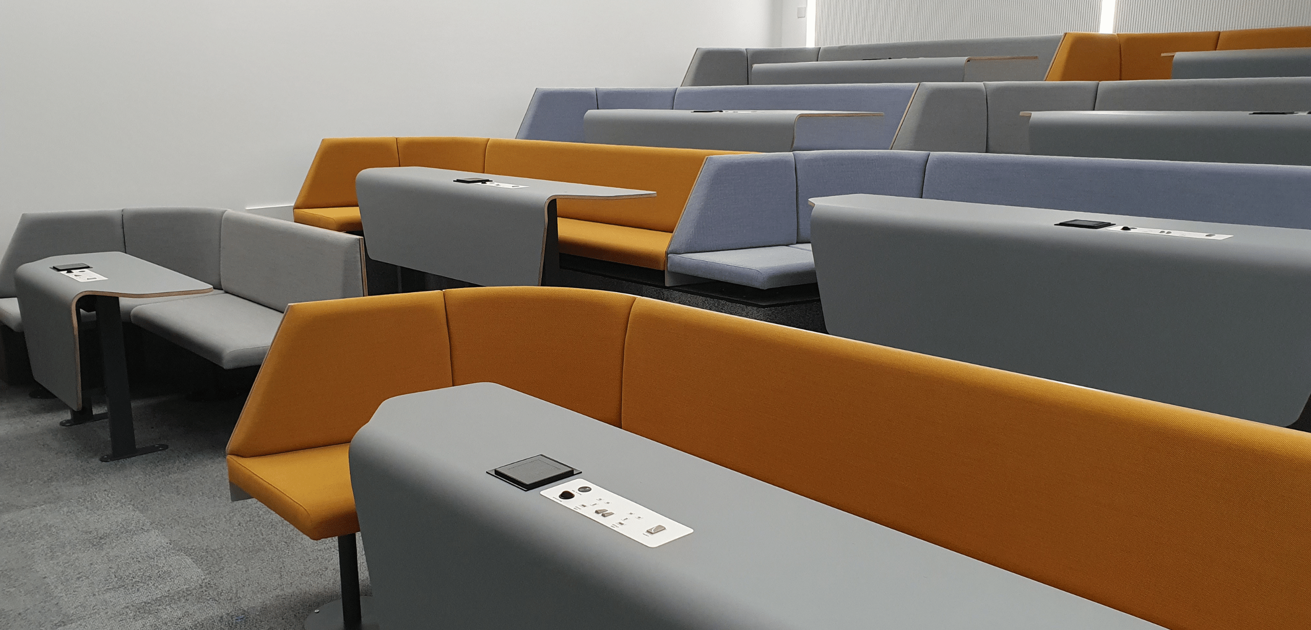 A lecture room with orange and yellow lecture hall seating