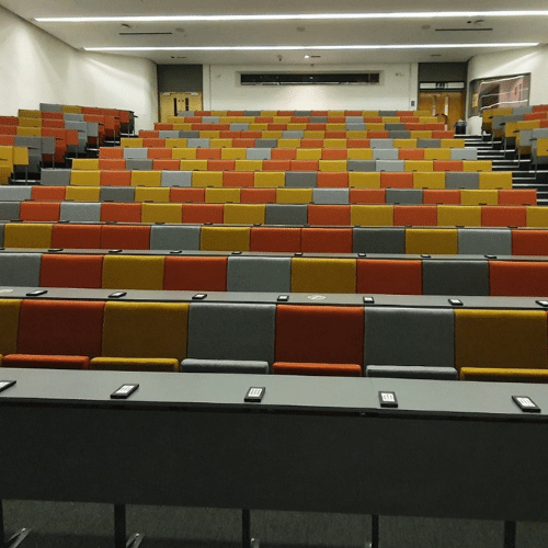A lecture hall with rows of seats that have been through auditorium seating refurbishment