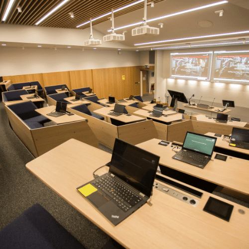 A lecture hall with lecture hall seating and laptops.
