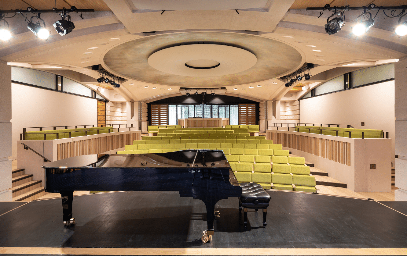 A grand piano in an auditorium with tiered seating