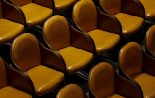 A row of brown leather seats in an auditorium.