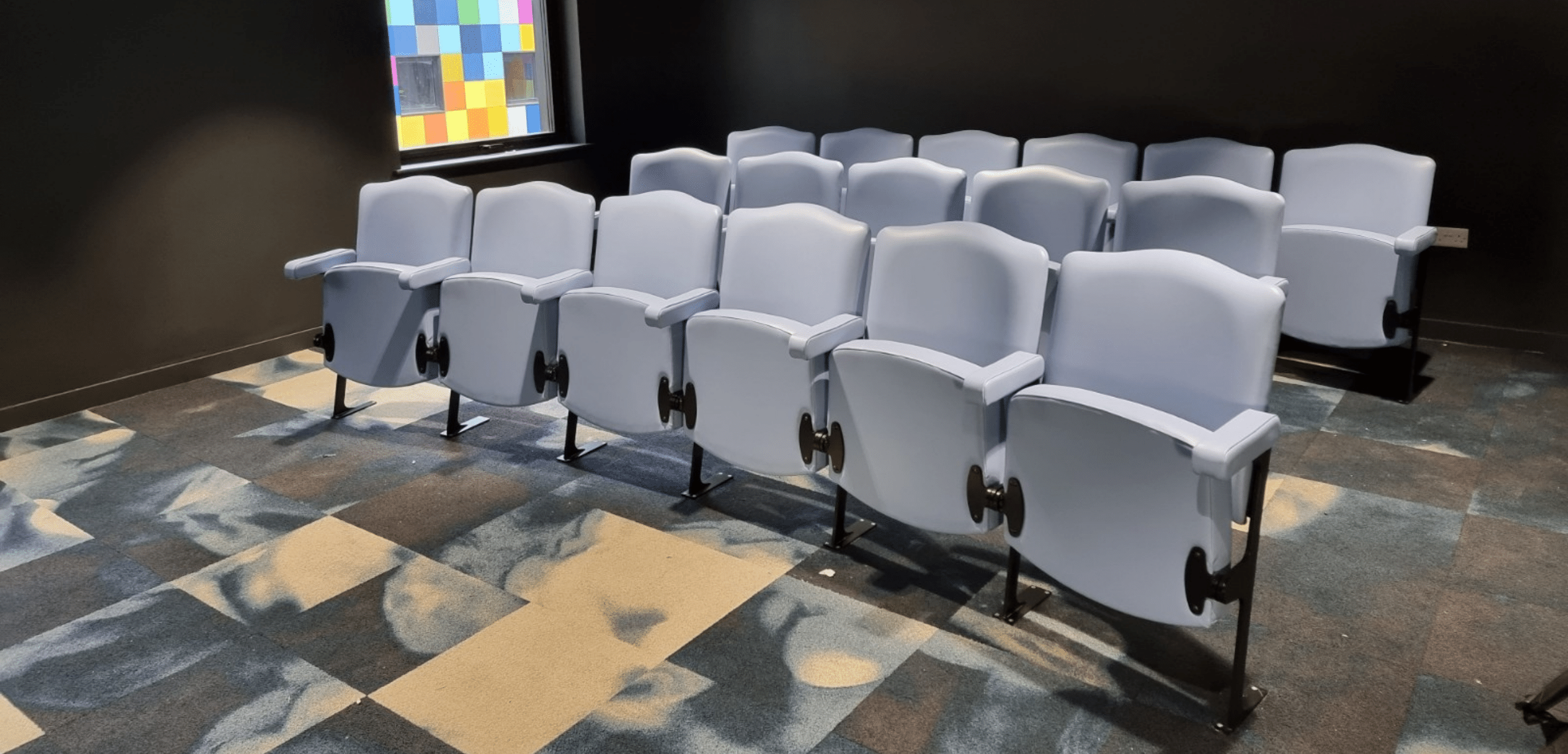 Rows of blue tip up seating in a room.
