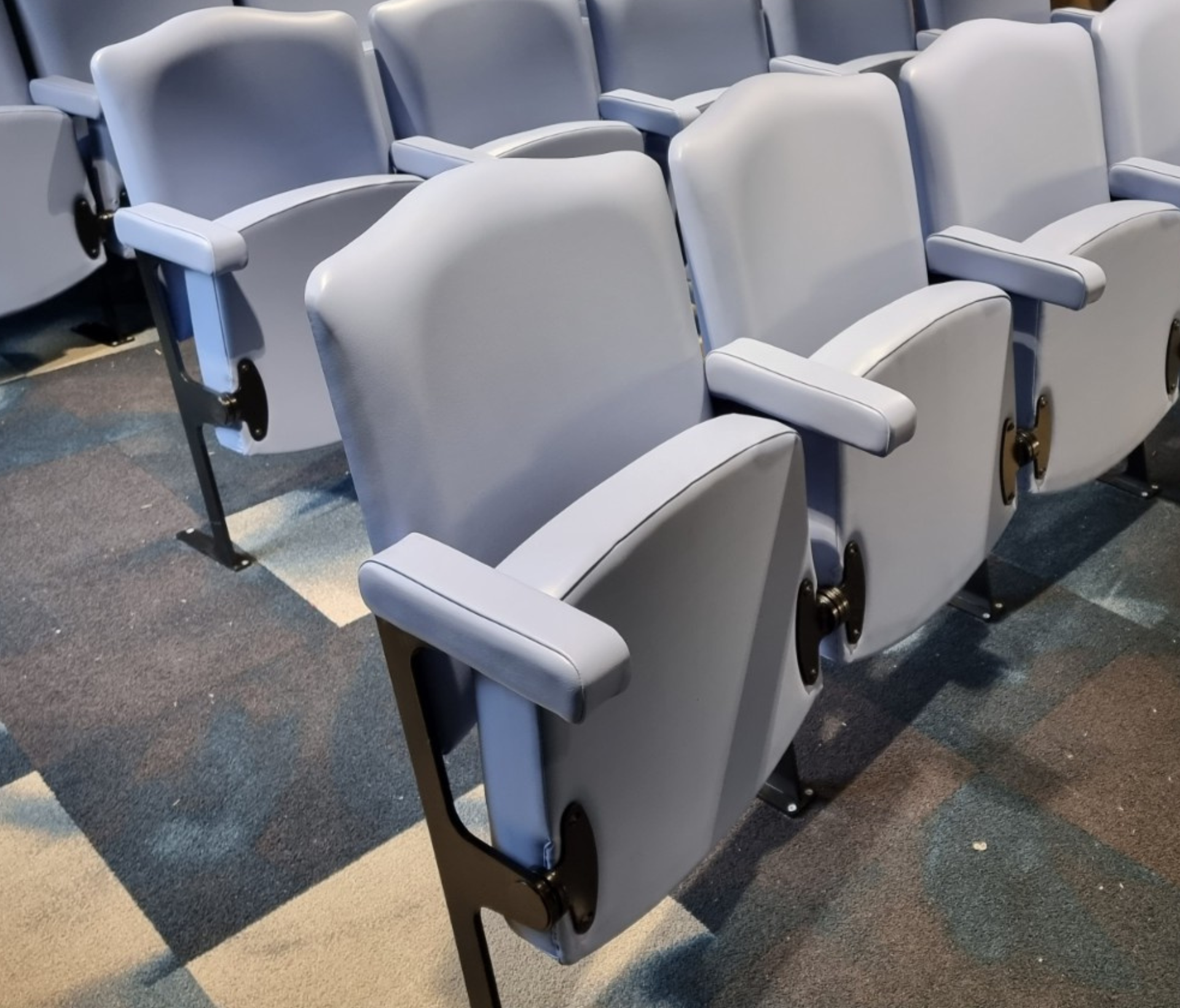 Rows of blue tip up seating in a room.