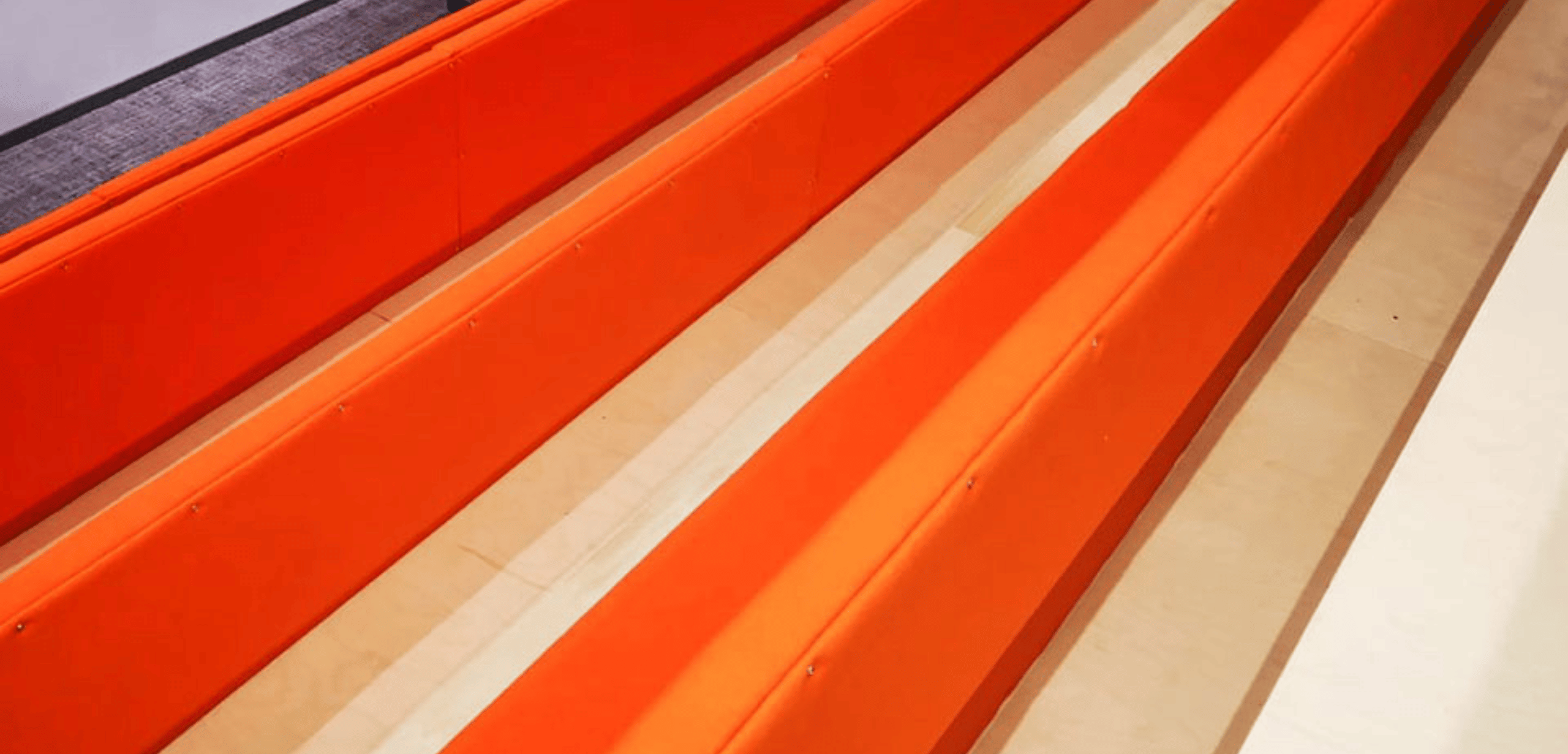 A row of orange tiered seating in a stadium.