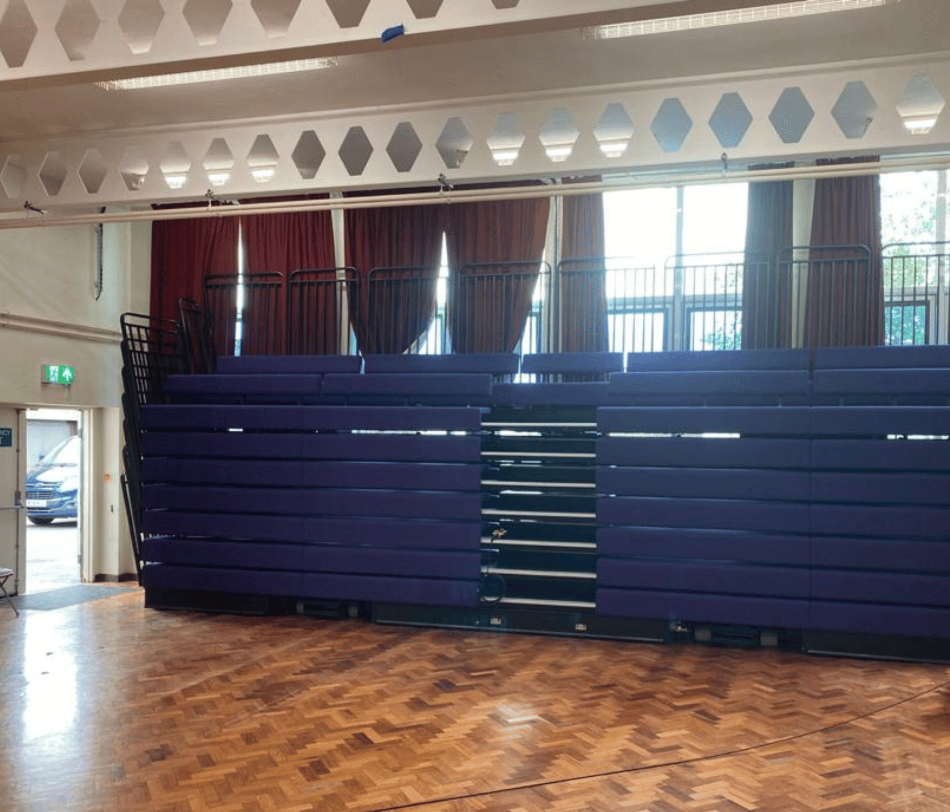 A wooden floor in a gymnasium with retractable seating stacked up