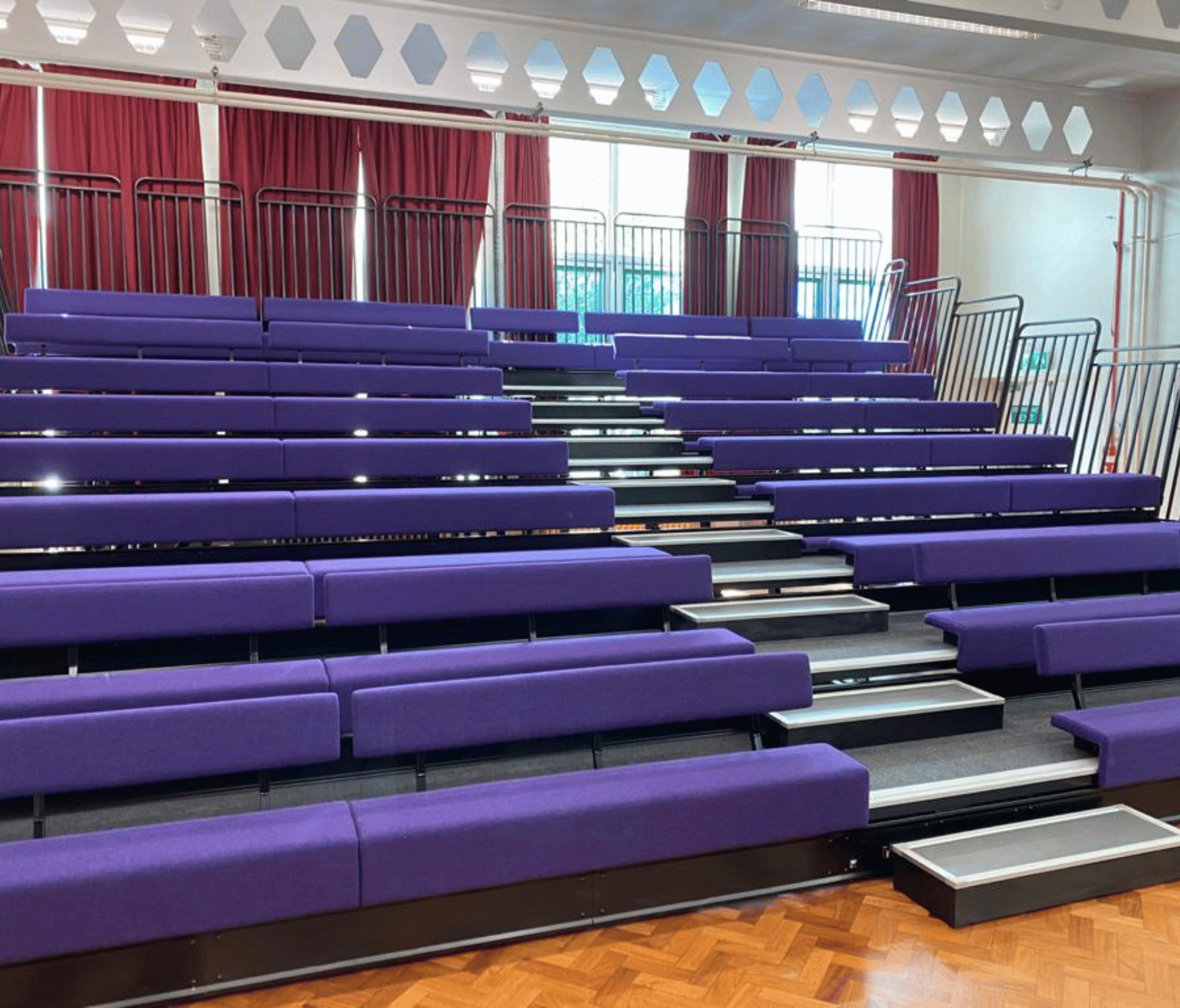 A large auditorium with purple retractable seating and stairs.