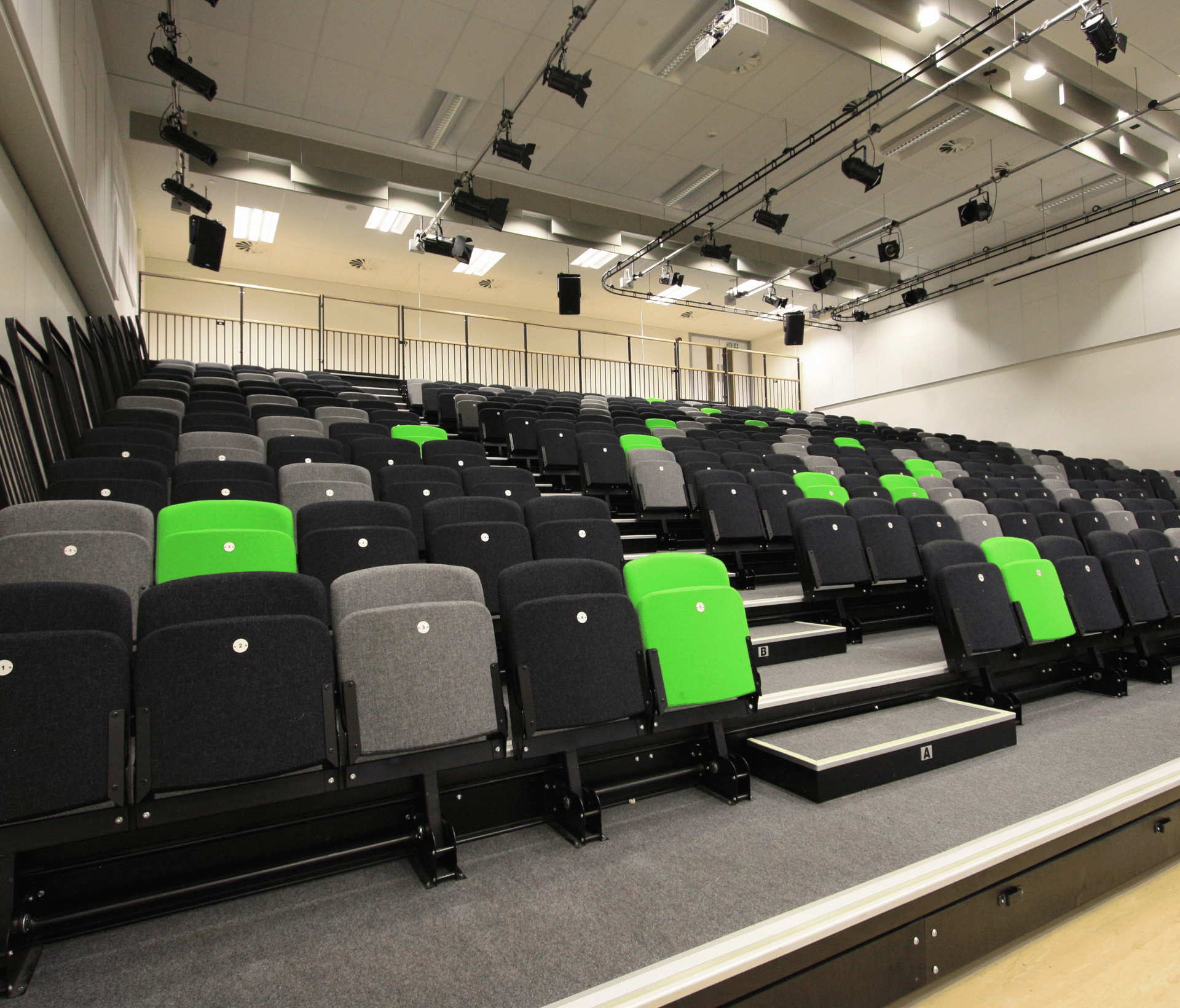 A large auditorium with green and black tip up seating