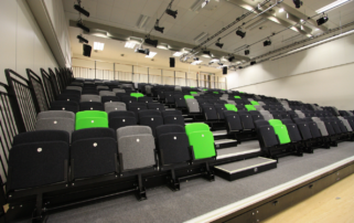 A large auditorium with rows of tiered seating and stairs.