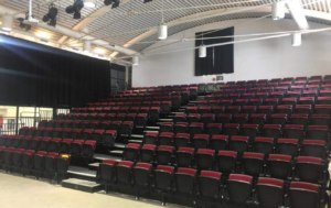 A large auditorium with rows of tiered seating and stairs.