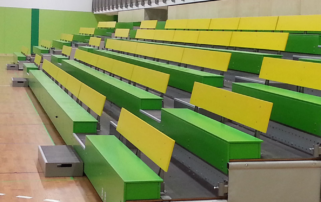 Green and yellow bleachers in a gymnasium.