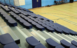 tiered seating with blue seats overlooking a sports hall