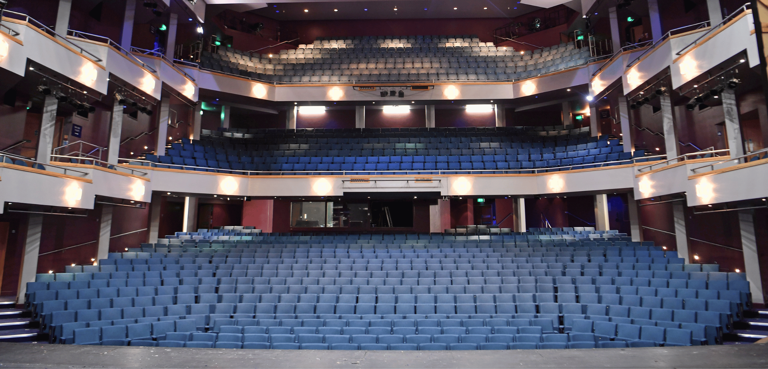 An auditorium with rows of blue theater style seating.