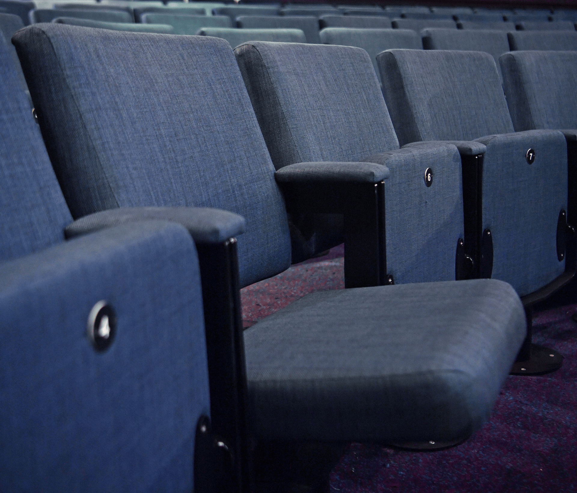 A row of blue auditorium seating in an auditorium.