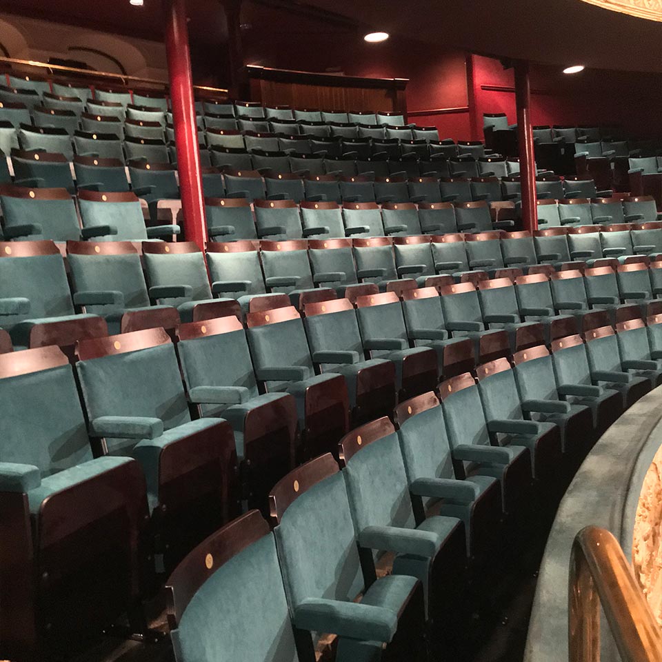 An empty auditorium with blue theater style seating